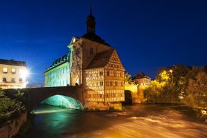 evening in Bamberg Germany with lighted historical city hall on river Regnitz