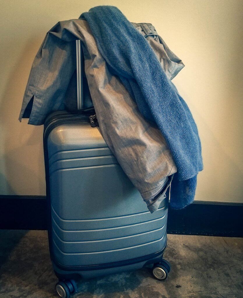 grey hard-sided luggage with jacket and blue scarf