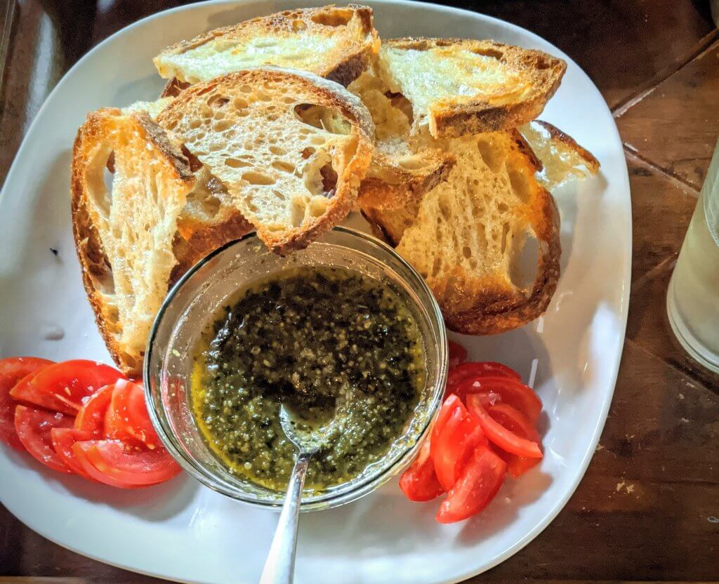 Basil pesto, bread and tomato on a plate