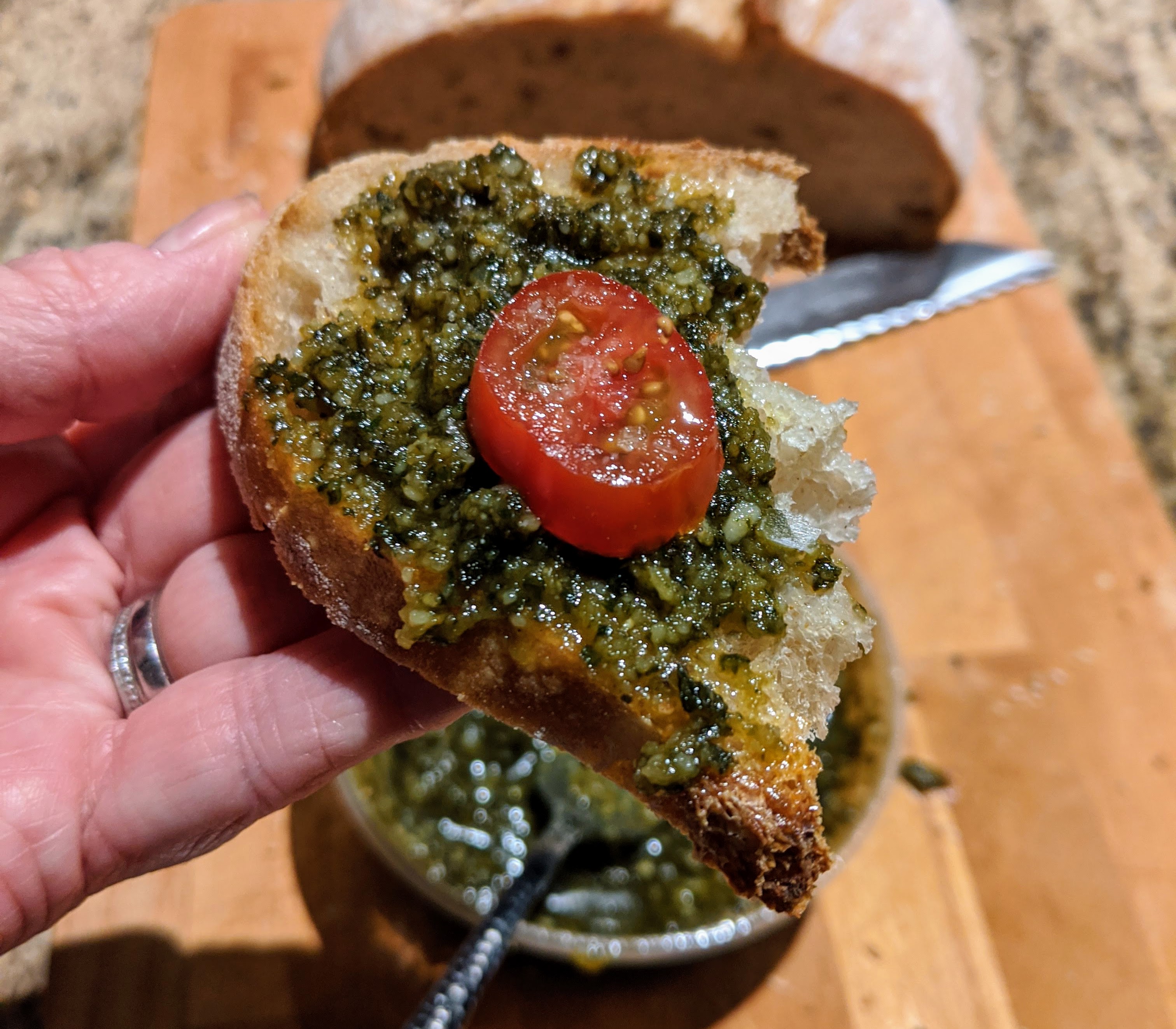 Basil pesto, bread and tomato in hand